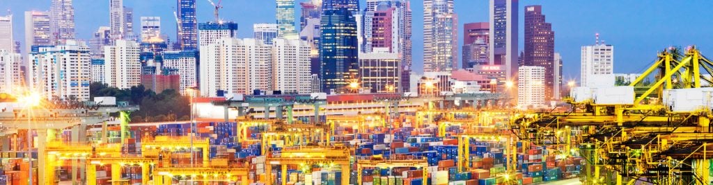 Elevated view of container port at dusk, with Singapore financial district and skyline